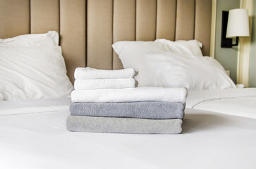 folded terry towels lie on clean white bed. Cleaning in guest room of hotel, cleanliness, laundry