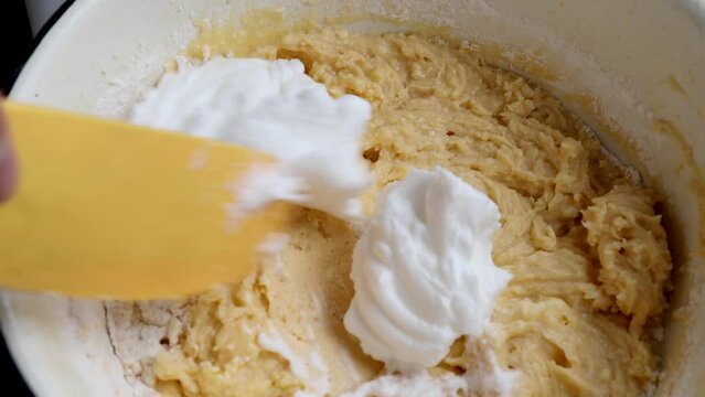 Mix the beaten yolks and whites with a silicone spatula. Stages of preparation of cuca de banana. Silicone spatula to stir the dough