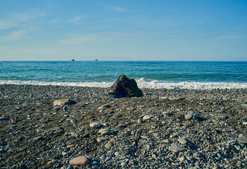 A couple in love on the pebble beach on a bright day with some distant boat in the background