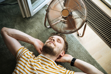 Heat wave during a summer, a man finds respite at his home balcony with the help of an electric...