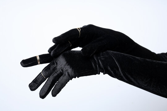 Female hands in black gloves with rings on white background