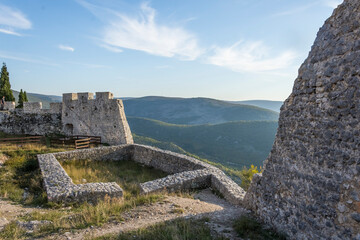 Ruins of a medieval castle with vegetation coming back and a panoramic view of the valley bellow