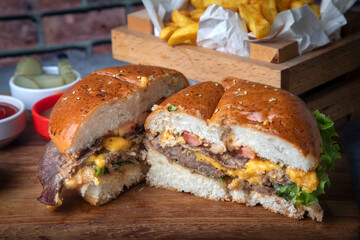 Homemade hamburger served with french fries. It looks delicious prepared with onions, hamburger patties, cheddar cheese and ham.