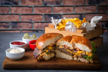 Homemade hamburger served with french fries. It looks delicious prepared with onions, hamburger patties, cheddar cheese and ham.