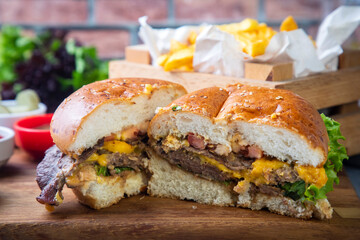 Homemade hamburger served with french fries. It looks delicious prepared with onions, hamburger patties, cheddar cheese and ham.