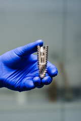 Dental implant. Dentist hold a model of dental implant in hand.  Concept of implantation teeth and dental surgery. Space for text. Hand in glove showing the installation of a dental implant. Closeup.