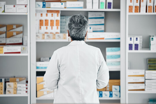 Stock, back and pharmacist at a medicine shelf for healthcare, medical work and service at a pharmacy. Doctor, pills and pharmaceutical worker looking at the coice of drugs while working at a clinic