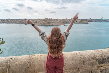 woman standin at a wall looking at a panoramic view of the three cities in valletta