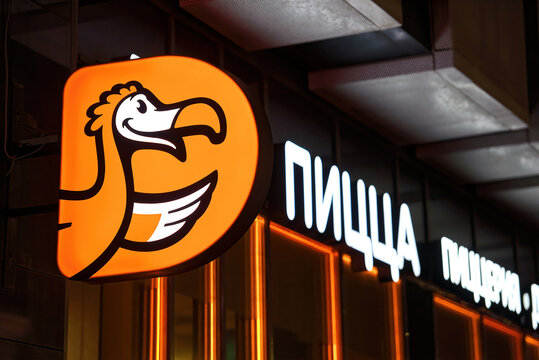 Minsk, Belarus. Sep 2022. Dodo Pizza illuminated neon sign on restaurant`s facade at night. Dodo pizzeria restaurant sign, Russian and Europe pizza chain. Fast food restaurant in the centre of Minsk.