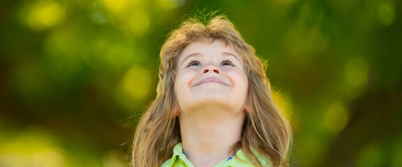 Close up portrait of cute child outdoors. Spring banner for website header. Closeup headshot portrait of smiling little boy on nature