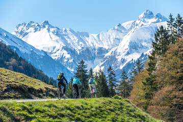 Fototapeta na wymiar Drei Radfahrer vor traumhafter Bergkulisse im Oberallgäu nahe Oberstdorf