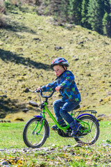 Kleiner Junge befährt mit seinem Rad einen Feldweg im Frühling