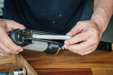 carpenter using nail gun or brad nailer tool ,load a top loading stapler  in a workshop ,furniture...