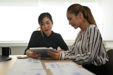 Obraz premium Two successful business partner discussing work, working on social media strategy together in bright office