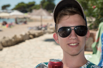 zadowolony chłopak pijący napój na plaży w słońcu