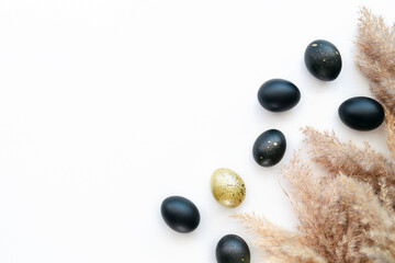 Eggs painted gold and black on white background. Minimal Easter concept with copy space for text. Golden luxury backdrop