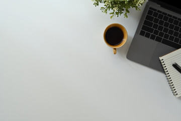 Laptop computer, cup of coffee and notebook on white office desk. Top view with copy space for your text
