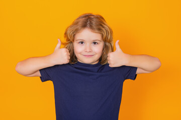 Child showing thumbs up on studio isolated background. Kid boy making thumbs up sign. Happy kid, happy and smiling emotions.