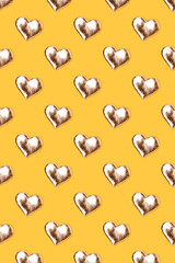 Pattern made of golden hearts on a yellow background.