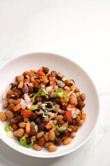 High in protine boiled black chana or chickpea salad. Chopped tomatoes, onion, chilies, and coriander mixed with boiled peanuts or bengal gram. Weight loss meal. Served with Lemon. Copy space.