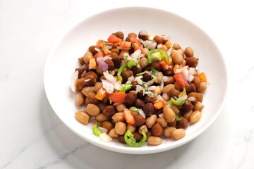 High in protine boiled black chana or chickpea salad. Chopped tomatoes, onion, chilies, and coriander mixed with boiled peanuts or bengal gram. Weight loss meal. Served with Lemon. Copy space.