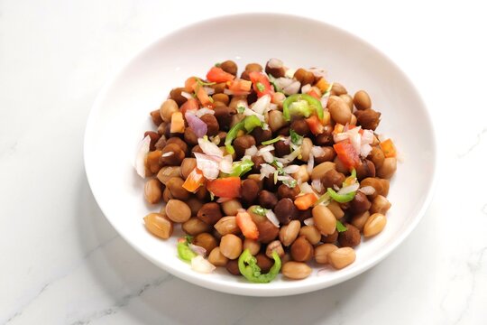 High in protine boiled black chana or chickpea salad. Chopped tomatoes, onion, chilies, and coriander mixed with boiled peanuts or bengal gram. Weight loss meal. Served with Lemon. Copy space.