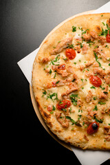 Fragment of top view on pizza with cherry tomatoes and chicken garnished by green