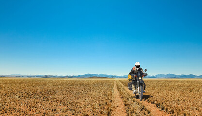 One Motorbiker driving on dirt road through grasland desert. Motorcycle Adventure in Namib, Namibia. - 567304953