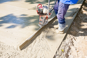 Worker is using power tool with engine, compactor, for level and compact fresh concrete - obrazy, fototapety, plakaty