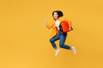 Side view young woman in summer casual clothes jump high hold suitcase run isolated on plain yellow...