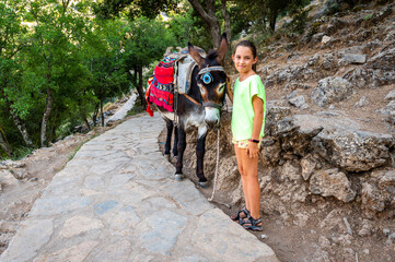 Girl riding a donkey to visit Cave of Diktaion Andron.