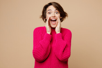 Young promoter fun woman wear pink sweater scream sharing hot news about sales discount with hands near mouth isolated on plain pastel light beige background studio portrait. People lifestyle concept.