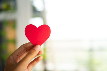 Hands holding heart with minimalist interior background