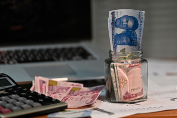 Glass jar filled with the new 1000naira, 500naira, 200naira note, with other denomination scatter  on  on an office table close to a computer