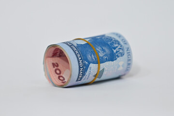 roll of new Naira tied with rubber band laying on white tabletop