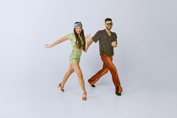Coordinated steps. Attractive young couple, man and woman in retro clothes dancing disco isolated...