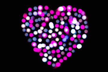 Blurred fuchsia, white and gray confetti in the shape of a heart with bokeh effect on a black background (backdrop for Valentines Day)