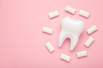 White healthy tooth model and heap of chewing gums on pink background. Concept of oral dental hygiene. Space for text