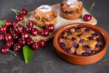 Red fresh cherries on a dark table with baked goods 