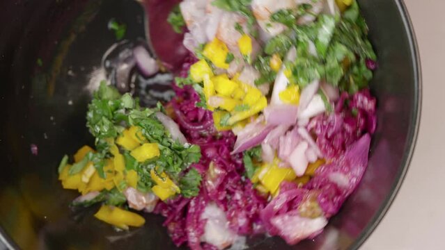 Chef prepares cebiche by spooning ingredients into bowl,