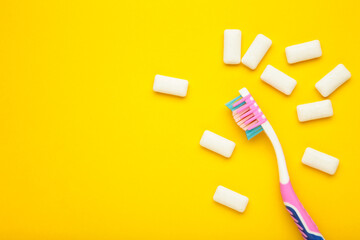 Toothbrush and chewing gums on yellow background. Minimal concept. Space for text