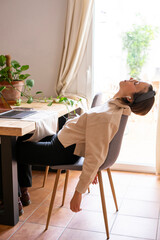 girl working at home.  Girl leaning on the chair and letting her arms drop from exhaustion