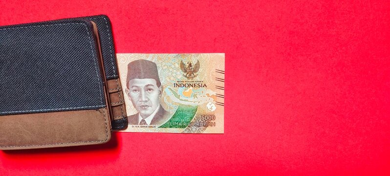 5.000 Indonesian rupiah new edition and wallet isolated on red background. Top view