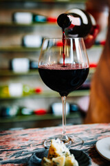 Waiter pouring red wine in glasses for wine on the table in restaurant