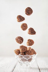 Falling chocolate truffles covered wafer crumbs. Praline chocolates in a bowl