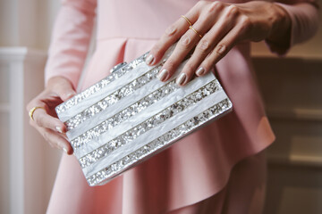 detail photograph of a hand holding an elegant, shiny party bag with a good manicure