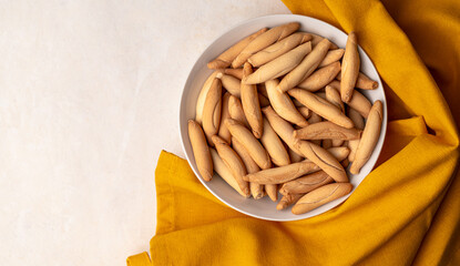 Flat lay with Bowl with picos - bread sticks on the beige background with yellow textile napkin. Copy space