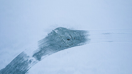 Tracks of the car on the snowy lake. Top down view, winter time. 