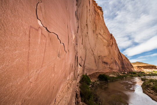 A pictograph on a rock wall above a river.