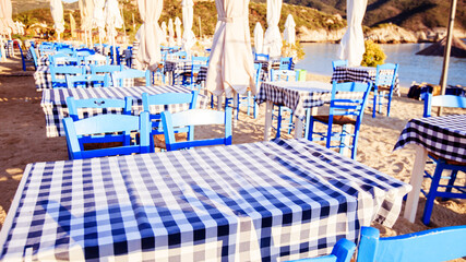 Traditional Greek restaurant, taverna on the beach at morning. - obrazy, fototapety, plakaty